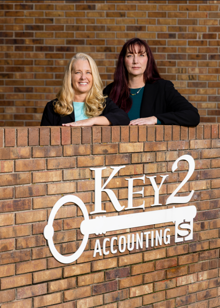 Hawaii Bookkeeping Services Image - Two smiling women sitting across from one another, doing paperwork and smiling